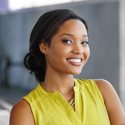 A smiling woman in a yellow top posing for the camera with a neutral background.