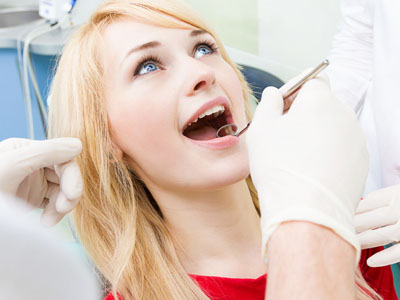A young woman with open mouth under dental care, receiving dental treatment in a professional setting.